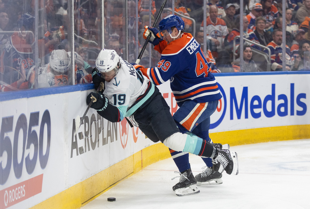 Seattle Kraken's Jared McCann (19) is checked by Edmonton Oilers' Ty Emberson (49) during third period NHL action, in Edmonton on Tuesday March 31, 2026. (Jason Franson/The Canadian Press via AP)