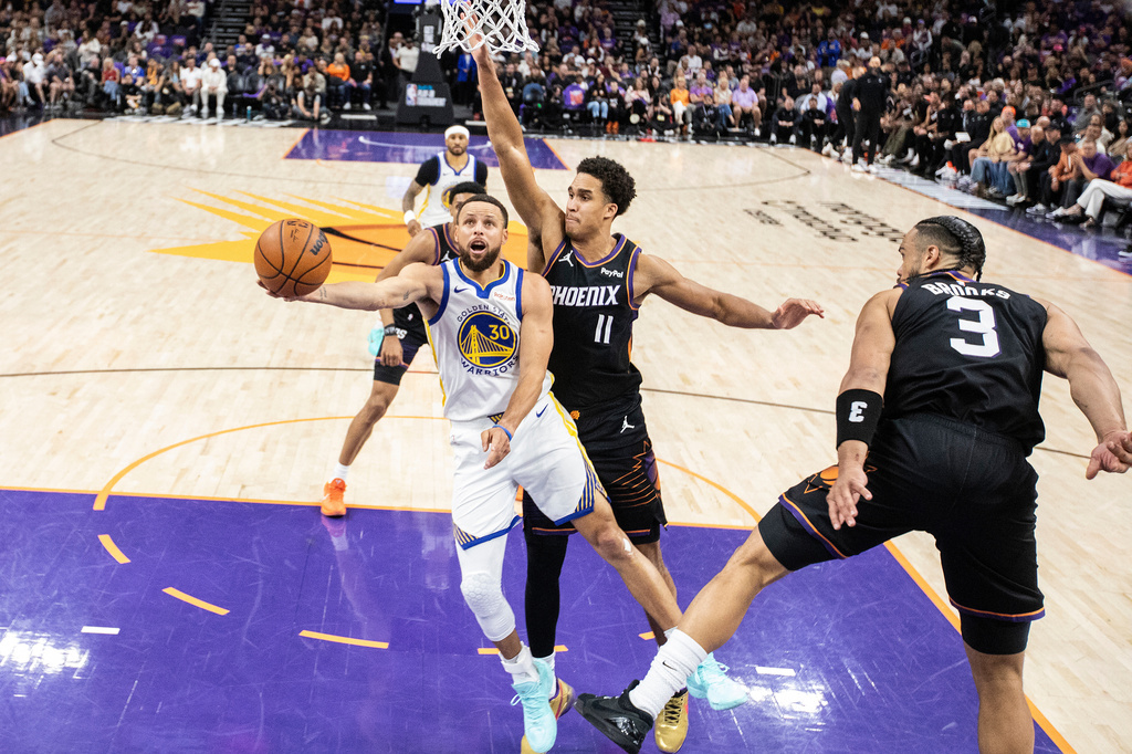 Golden State Warriors guard Stephen Curry (30) drives for a layup as Phoenix Suns forward Oso Ighodaro (11) defends during the first half of their NBA play-in tournament game at Mortgage Matchup Center in Phoenix, Ariz., Friday, April 17, 2026. (Stephen Lam/San Francisco Chronicle via AP)