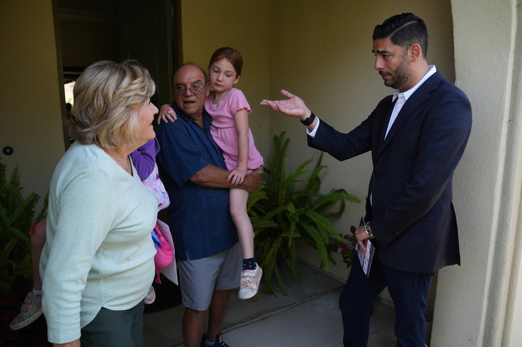 Ammar Campa-Najjar, right, a Democratic candidate for California's 48th Congressional District, speaks with a family as he canvasses in a neighborhood Saturday, May 23, 2026, in San Marcos, Calif. (AP Photo/Gregory Bull)
