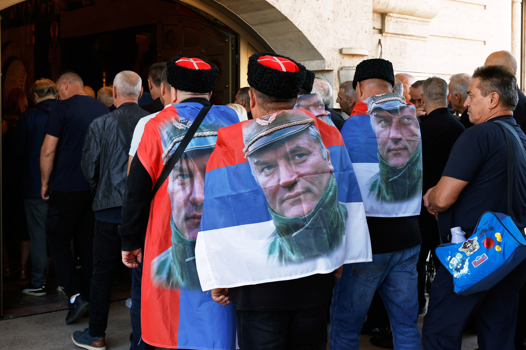 People line up to pay their respects to the former Bosnian Serb army commander Ratko Mladic, seen on the flags, who died last week while serving a life sentence for genocide and other atrocities during the war in Bosnia, at the St. Luka Church, in Belgrade, Serbia, Monday, Sept. 7, 2026. (AP Photo/Marko Drobnjakovic)
