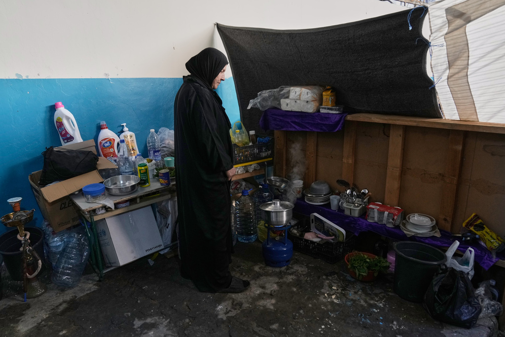 A displaced woman who fled Israeli airstrikes with her family in southern Lebanon cooks food at a school being used as a shelter in Beirut, Lebanon, Tuesday, March 17, 2026. (AP Photo/Bilal Hussein)