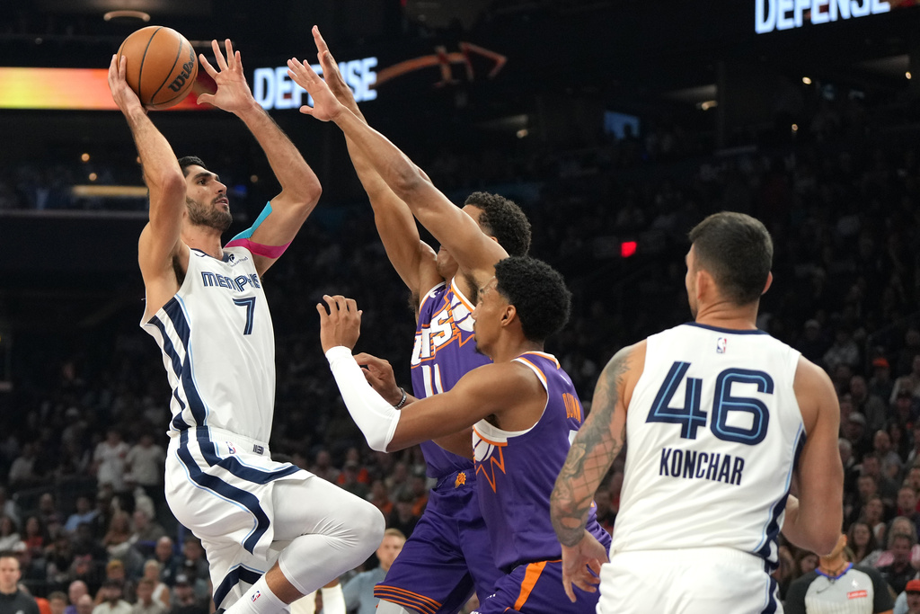 Memphis Grizzlies forward Santi Aldama (7) shoots over Phoenix Suns forward Oso Ighodaro (11) and forward Ryan Dunn during the first half of an NBA basketball game, Wednesday, Oct. 29, 2025, in Phoenix. (AP Photo/Rick Scuteri)