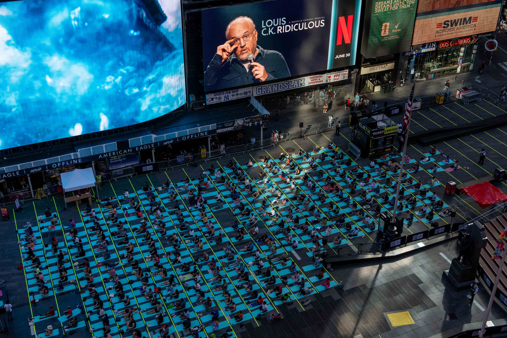 People participate in a mass yoga class during the "Times Square: Mind Over Madness Yoga" event, to celebrate the summer solstice, Sunday, June. 21, 2026, in New York (AP Photo/Adam Gray)