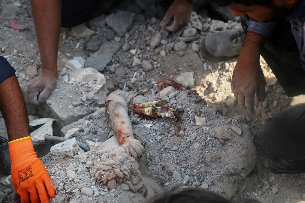 The arm of a deceased person is seen protruding from the rubble as rescue workers and residents search in the aftermath a strike on a girls' elementary school in Minab, Iran, Saturday, Feb. 28, 2026. (Abbas Zakeri/Mehr News Agency via AP)