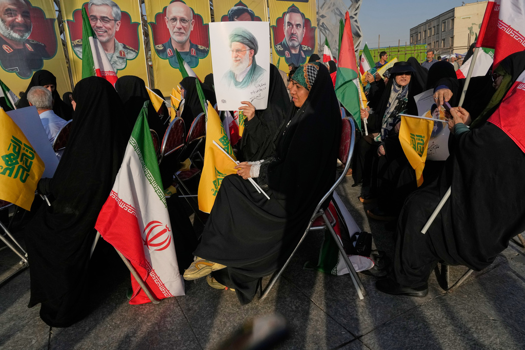A woman holds a poster of the Iranian Supreme Leader Ayatollah Ali Khamenei as portraits of the late Iranian armed forces commanders, who were killed in Israeli strike in June, are seen at background, during a commemoration marking the first death anniversary of Hezbollah leaders Hassan Nasrallah and Hashem Safieddine, who were killed in Israeli airstrikes in Beirut, in Tehran, Iran, Thursday, Oct. 2, 2025. (AP Photo/Vahid Salemi)
