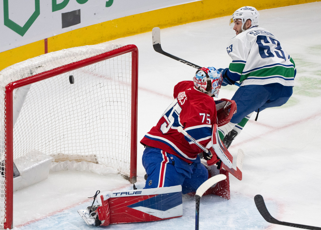 Vancouver Canucks' Max Sasson (63) scores against Montreal Canadiens goaltender Jakub Dobes (75) during second-period NHL hockey game action in Montreal, Monday, Jan. 12, 2026. (Christinne Muschi/The Canadian Press via AP)