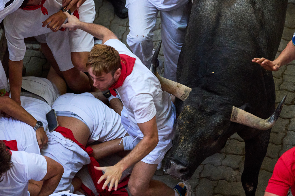 Revelers run alongside Jose Escolar's fighting bulls during the fifth running of the bulls at the San Fermín festival in Pamplona, Spain, Saturday, July 11, 2026. (AP Photo/Miguel Oses)