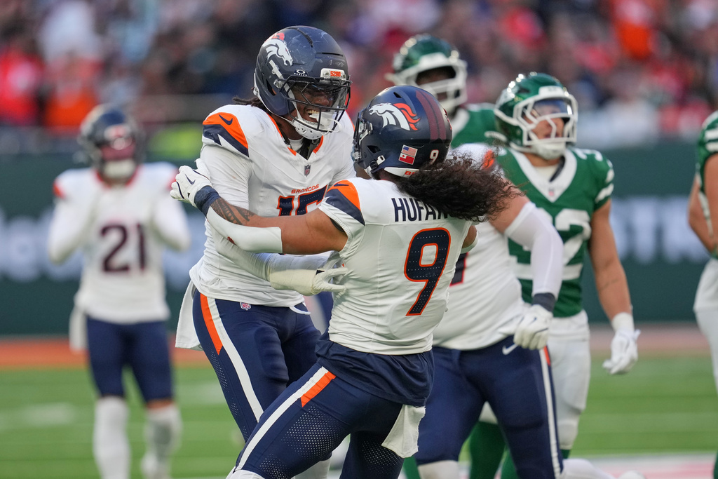 Denver Broncos safety Talanoa Hufanga (9) and Denver Broncos linebacker Nik Bonitto (15) celebrate after sacking New York Jets quarterback Justin Fields (7) in the second half of an NFL football game between the Denver Broncos and the New York Jets, Sunday, Oct. 12, 2025, in London. (AP Photo/Kin Cheung)