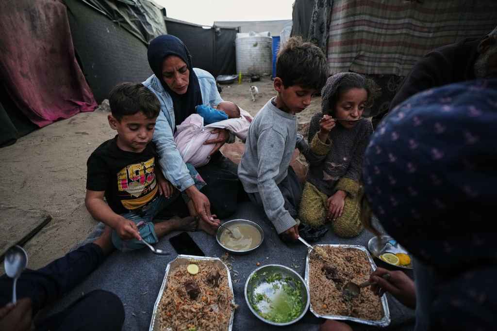 Displaced members of the Al-Zamli family break their fast on the first day of Ramadan inside their tent in Khan Younis, Gaza Strip, Wednesday, Feb. 18, 2026. (AP Photo/Jehad Alshrafi)