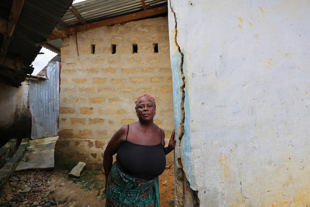Marie Pearl stands by her house, which has developed cracks that she blames on blasting at a nearby mine site in Gold Camp, Liberia, July 8, 2025. (AP Photo/Misper Apawu)