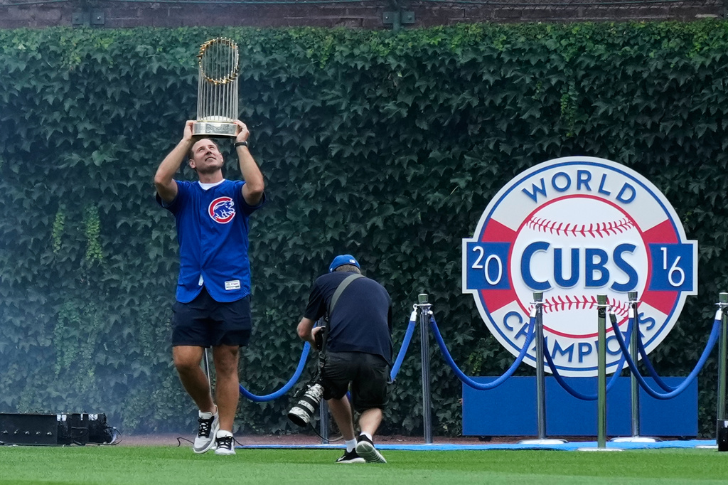 Former Chicago Cubs first baseman Anthony Rizzo holds up the 2016 World Series Championship trophy as his walks on the field before a baseball game between the Minnesota Twins and the Chicago Cubs in Chicago, Saturday, July 18, 2026. (AP Photo/Nam Y. Huh)
