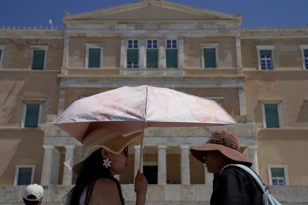 Tourists wearing hats visit the Tomb of the Unknown Soldier outside the Greek Parliament in Athens, Greece, Wednesday, Aug. 12, 2026. (AP Photo/Thanassis Stavrakis)