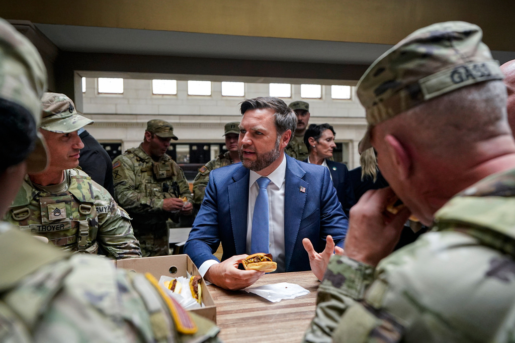 Vice President JD Vance eats a Shake Shack hamburger as he meets with members of the National Guard at Union Station in Washington, Wednesday, Aug. 20, 2025. (Alexander Drago/Pool via AP)