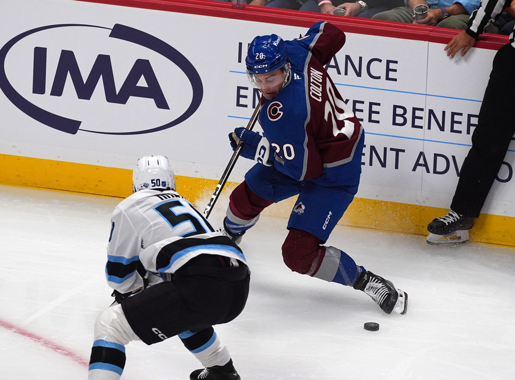 Colorado Avalanche center Ross Colton (20) collects the puck as Utah Mammoth defenseman Sean Durzi (50) covers in the first period of an NHL hockey game Thursday, Oct. 9, 2025, in Denver. (AP Photo/David Zalubowski)