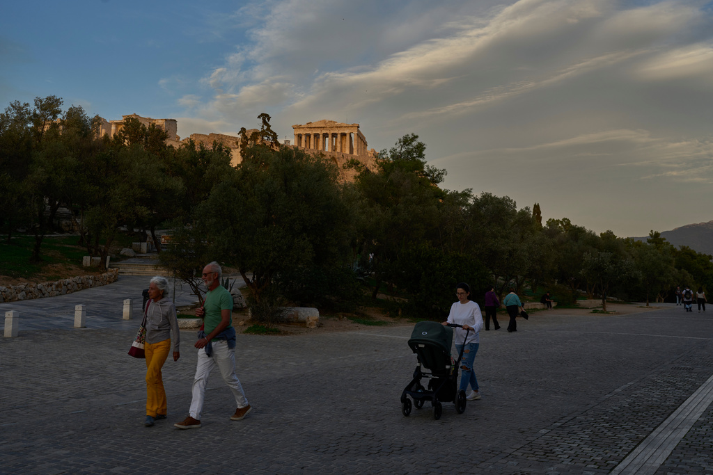 Pedestrians walk in front the Acropolis hill and the Parthenon temple in Athens, Monday, Oct. 27, 2025. (AP Photo/Petros Giannakouris)