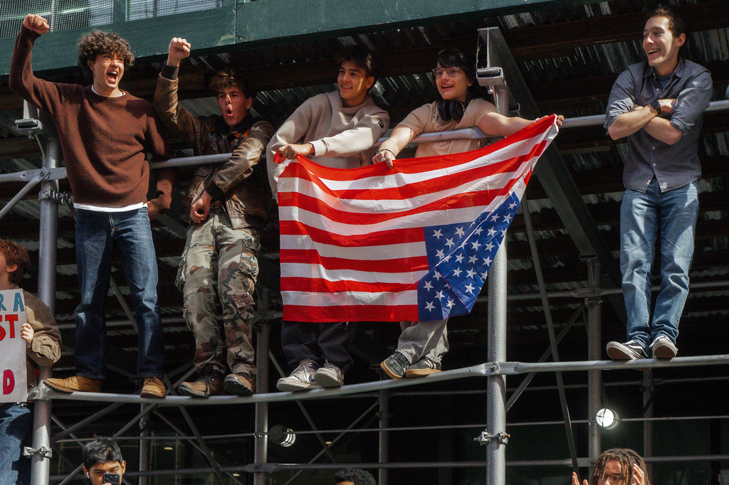 Protesters holding a U.S. flag upside down shout slogans from scaffolding during a "No Kings" protest Saturday, Oct. 18, 2025, in New York. (AP Photo/Olga Fedorova)