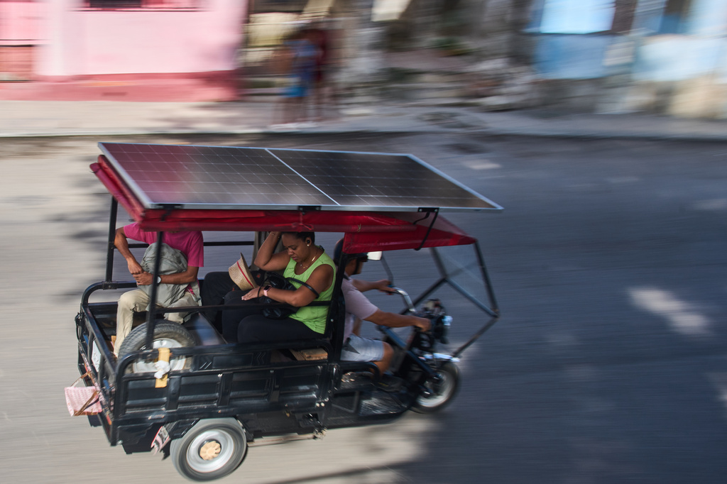 People ride in an electric tricycle equipped with a solar panel in Havana, Cuba, Friday, July 10, 2026. (AP Photo/Ramon Espinosa)