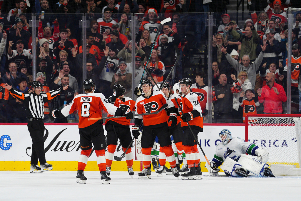 Philadelphia Flyers' Christian Dvorak, center, celebrates with teammates after his goal against Vancouver Canucks goaltender Thatcher Demko, right, during the third period of an NHL hockey game, Monday, Dec. 22, 2025, in Philadelphia. (AP Photo/Derik Hamilton)