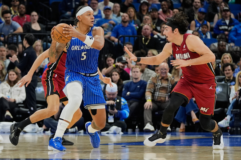 Orlando Magic forward Paolo Banchero (5) passes the ball as Miami Heat guard Jaime Jaquez Jr. defends during the first half of an NBA basketball game, Friday, Dec. 5, 2025, in Orlando, Fla. (AP Photo/John Raoux)