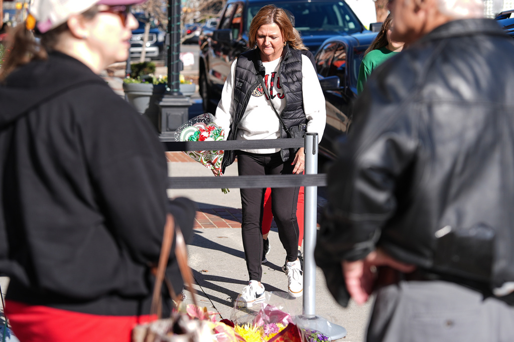 A supporter brings flowers to lay at the tribute at the NC Auto Racing Walk of Fame for Greg Biffle, Friday, Dec. 19, 2025, in Mooresville, N.C. (AP Photo/Matt Kelley)