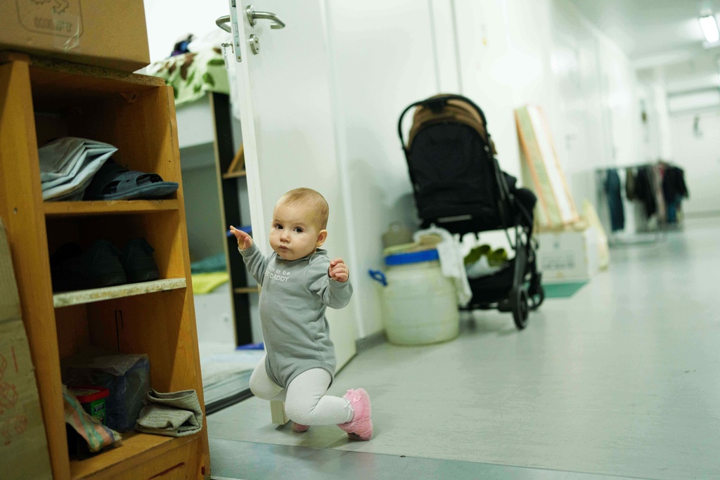 Sofia, 10 months-old, walks in a corridor at the hostel for internally displaced people in Bucha, Ukraine, on Sunday, Nov. 23, 2025. (AP Photo/Evgeniy Maloletka)