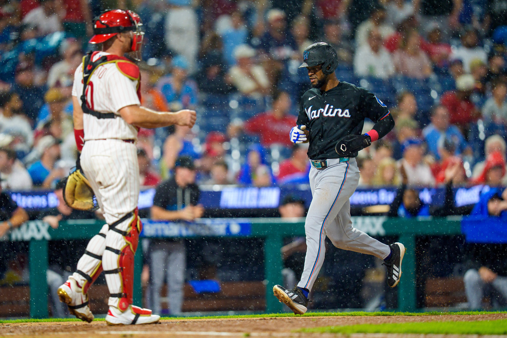 Miami Marlins' Otto Lopez, right, comes in to score on a single hit by Griffin Conine as Philadelphia Phillies catcher J.T. Realmuto, left, looks on during the sixth inning of a baseball game, Monday, Aug. 17, 2026, in Philadelphia. (AP Photo/Chris Szagola)
