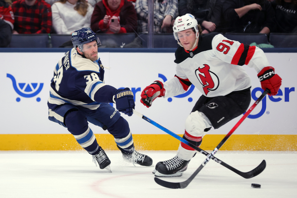 Columbus Blue Jackets forward Boone Jenner, left, knocks the puck away from New Jersey Devils forward Dawson Mercer during the first period of an NHL hockey game in Columbus, Ohio, Wednesday, Dec. 31, 2025. (AP Photo/Paul Vernon)
