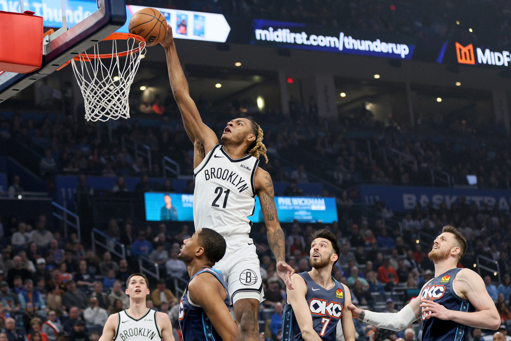 Brooklyn Nets forward Noah Clowney (21) dunks as Oklahoma City Thunder center Isaiah Hartenstein, right, Thunder center Chet Holmgren (7), Thunder guard Aaron Wiggins, second from left, and Nets guard Egor Demin, left, look on during the first half of an NBA basketball game Friday, Feb. 20, 2026, in Oklahoma City. (AP Photo/Nate Billings)