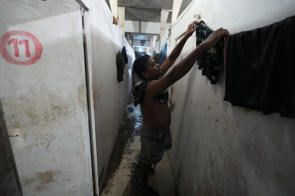 Sibaram Pradhan, a power loom factory worker, hangs clothes for drying after taking a bath at his residential quarters in Surat, India, Thursday, May 28, 2026. (AP Photo/Ajit Solanki)