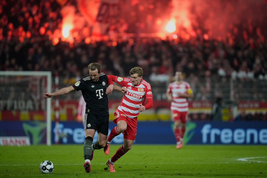 Bayern's Harry Kane, left, and Union's Aljoscha Kemlein challenge for the ball during the German soccer cup round of sixteen match between 1. FC Union Berlin and FC Bayern Munich in Berlin, Germany, Wednesday, Dec. 3, 2025. (AP Photo/Ebrahim Noroozi)