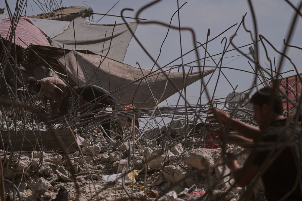 Palestinians remove iron from the rubble of buildings destroyed by Israeli airstrikes during the war with Hamas, repair and recycle it for construction, building tents or selling it, in Gaza City, Sunday, Aug. 16, 2026. (AP Photo/Jehad Alshrafi)