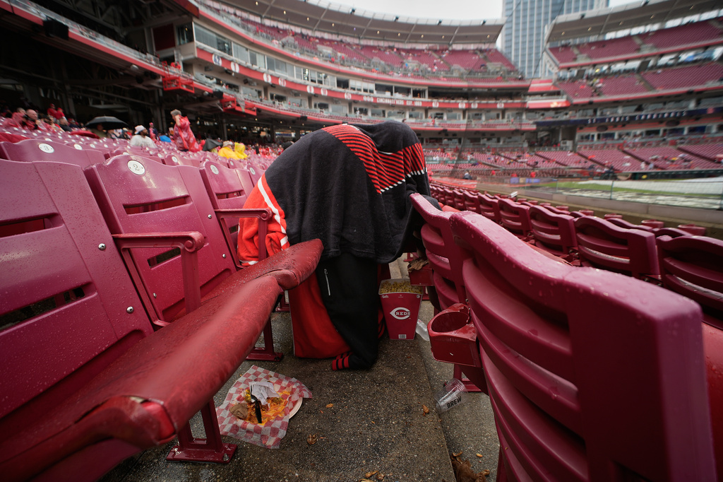A Cincinnati Reds fan sits under a blanket in the stands during a rain delay before a baseball game between the Reds and the St. Louis Cardinals was postponed in Cincinnati, Sunday, May 24, 2026. (AP Photo/Carolyn Kaster)