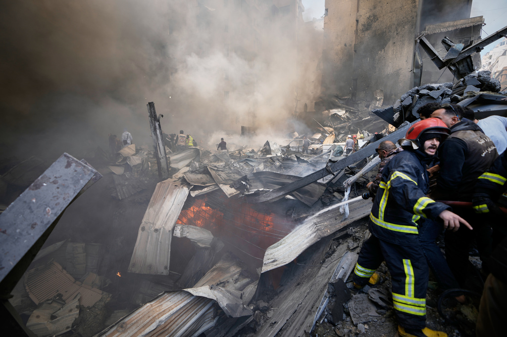 Firefighters, first responders, and volunteers work on smoldering debris at the site of an Israeli airstrike that struck an apartment building in Beirut, Lebanon, Wednesday, April 8, 2026. (AP Photo/Bilal Hussein)