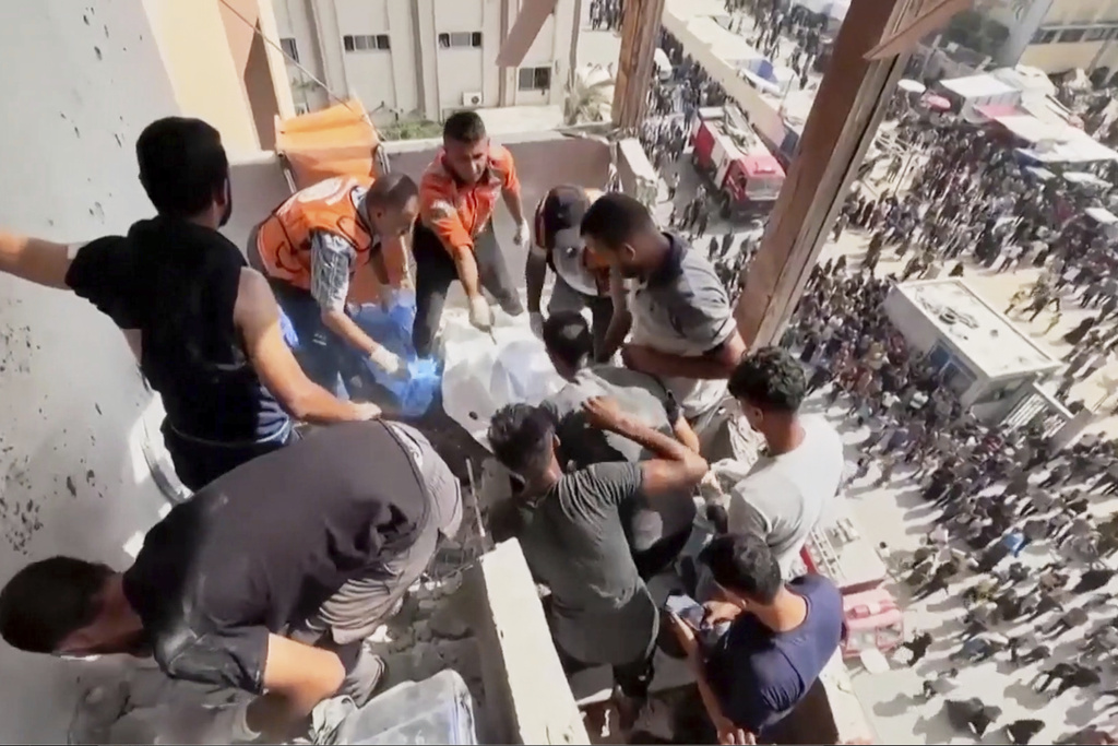 This frame grab taken from a video released by Reuters shows several people trying to remove a body from the the outside stairs of Nasser Hospital shortly after the first of two rounds of Israeli strikes in Khan Younis, southern Gaza Strip, Monday, Aug. 25, 2025. (Reuters via AP)