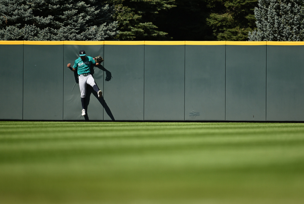 Seattle Mariners center fielder Julio Rodríguez slams into the wall after catching a fly ball in the fourth inning against the Colorado Rockies during a baseball game Sunday, Sept. 20, 2026, in Denver. (AP Photo/RJ Sangosti)