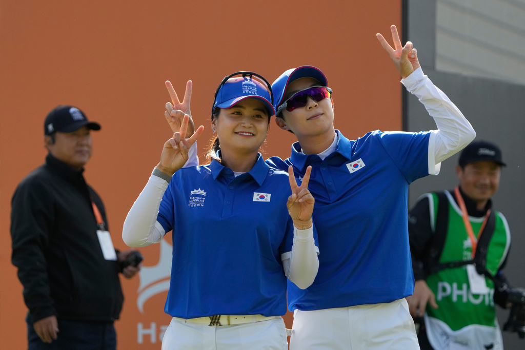 Hyo Joo Kim, right, and Hye-Jin Choi of South Korea acknowledge the gallery on the 1st hole during the pool B match against Sweden for the LPGA International Crown golf tournament at the New Korea Country Club in Goyang, South Korea, Thursday, Oct. 23, 2025. (AP Photo/Ahn Young-joon)