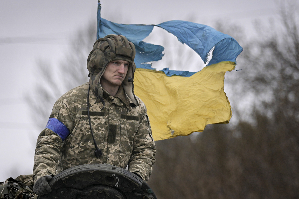 FILE - A Ukrainian serviceman is backdropped by his country's flag while standing on a tank, outside Kyiv, Ukraine, April 2, 2022.(AP Photo/Vadim Ghirda, File)