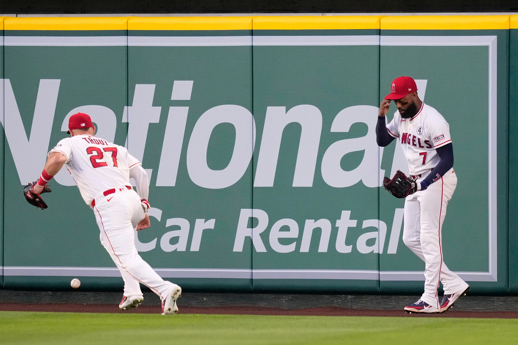 Los Angeles Angels right fielder Jo Adell touches his head after he misplayed a ball hit by Colorado Rockies' TJ Rumfield that hit him in the head and then bounced out for a solo home run as center fielder Mike Trout goes after the ball during the fourth inning of a baseball game Tuesday, June 2, 2026, in Anaheim, Calif. (AP Photo/Mark J. Terrill)