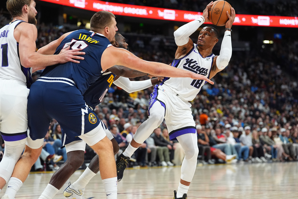 Sacramento Kings guard Russell Westbrook, right, looks to pass the ball as Denver Nuggets center Nikola Jokic, front left, and guard Tim Hardaway Jr. defend in the first half of an NBA basketball game Monday, Nov. 3, 2025, in Denver. (AP Photo/David Zalubowski)