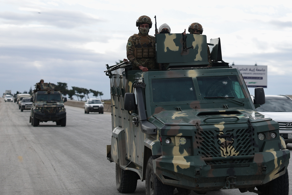 Syrian government soldiers stand on their armoured vehicle, as their convoy passes on a highway to the Deir Hafer village for a possible escalation fighting with the Kurdish fighters, in eastern Aleppo, Syrian, Wednesday, Jan. 14, 2026. (AP Photo/Ghaith Alsayed)