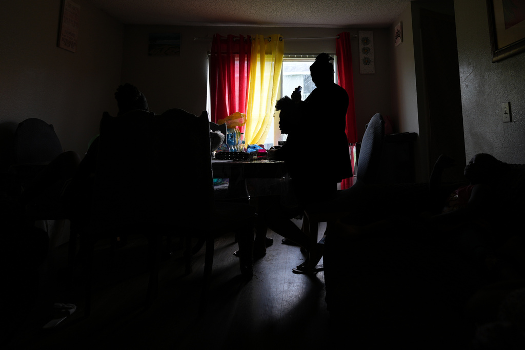 A Haitian immigrant braids another woman's hair inside a home shared by many members of a Haitian extended family, Tuesday, Aug. 19, 2025, in Orlando, Fla. (AP Photo/Rebecca Blackwell)