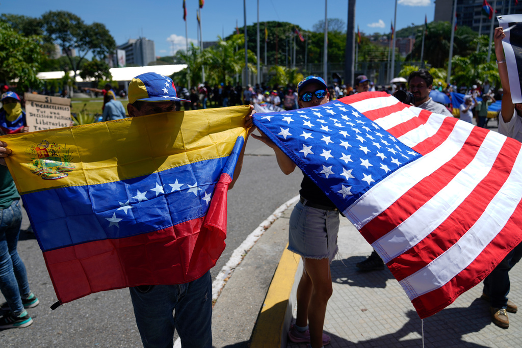 Demonstrators hold a Venezuelan and U.S. national flags during a student-led march calling for the release of people considered political prisoners on National Youth Day, in Caracas, Venezuela, Thursday, Feb. 12, 2026. (AP Photo/Ariana Cubillos)