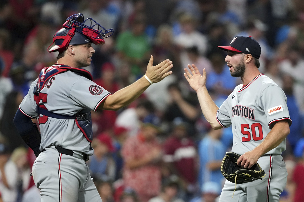 Washington Nationals' PJ Poulin, right, and Riley Adams celebrate after the Nationals won a baseball game against the Philadelphia Phillies Friday, Aug. 22, 2025, in Philadelphia. (AP Photo/Matt Slocum)