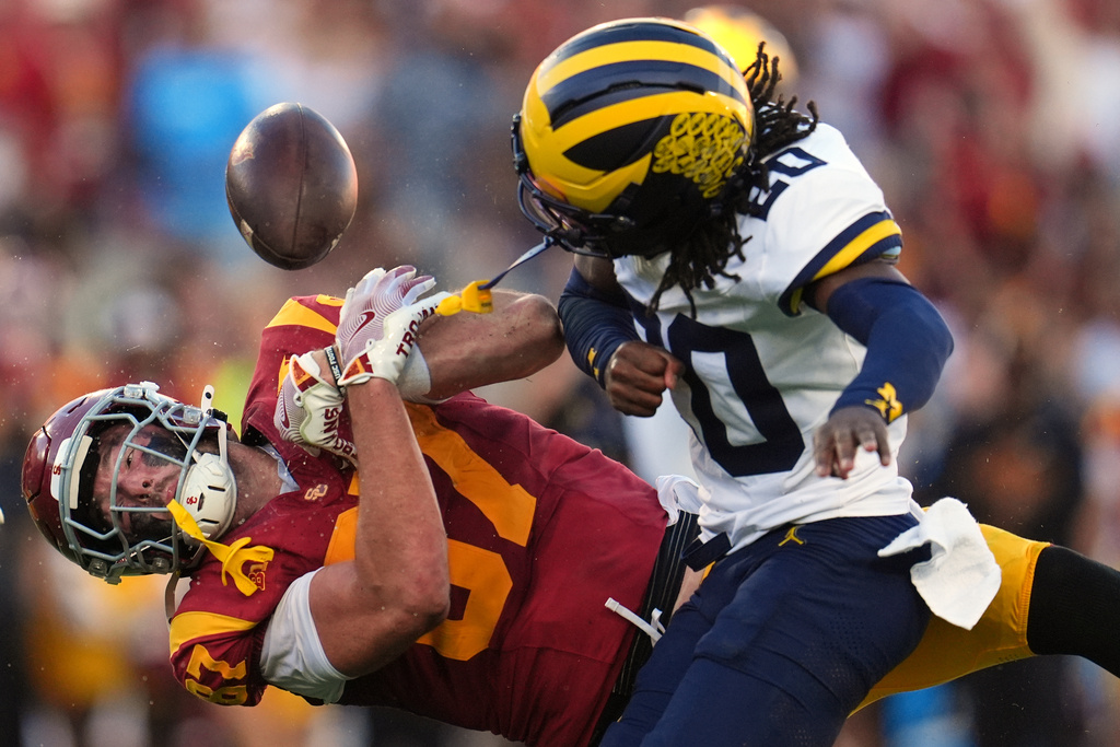 Southern California tight end Lake McRee (87) fumbles as he is hit by Michigan defensive back Jyaire Hill (20) during the first half of an NCAA college football game Saturday, Oct. 11, 2025, in Los Angeles. Michigan recovered the ball on the play. (AP Photo/Marcio Jose Sanchez)