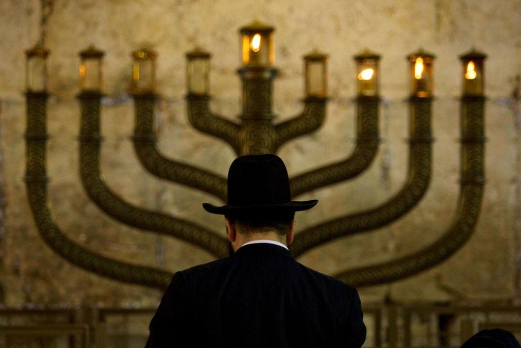 FILE - An Ultra-Orthodox Jewish man stands in front of a menorah on the third eve of Hanukkah, at the Western Wall, Judaism's holiest site in Jerusalem's old city, Sunday, Dec. 13, 2009. (AP Photo/Sebastian Scheiner, File)