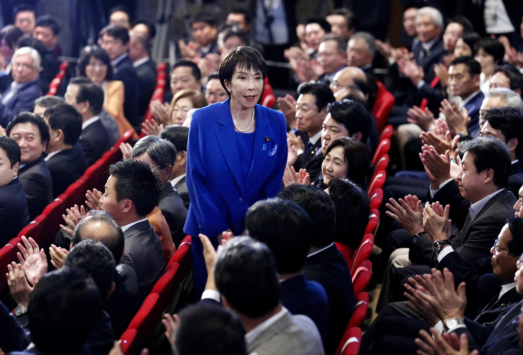 Former Economic Security Minister Sanae Takaichi, center, stands as Takaichi was chosen to a new leader of Japan’s ruling Liberal Democratic Party during the party's leadership election in Tokyo, Japan, Saturday, Oct. 4, 2025. (Kyodo News via AP)