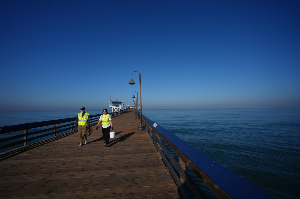 Justin Hamlin, left, and Maddie Tibayan, walk along the Imperial Beach pier after gathering a sample of seawater as part of a research team from the University of California, San Diego, Wednesday, March 11, 2026, in Imperial Beach, Calif. (AP Photo/Gregory Bull)