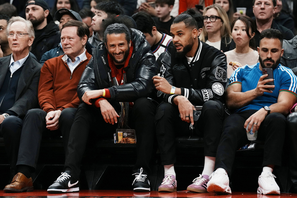 FILE - Colin Kaepernick, center left, sits beside Akim Aliu as they watch the Toronto Raptors take on the Boston Celtics in an NBA basketball game in Toronto, Dec. 5, 2022. (Chris Young/The Canadian Press via AP, File)
