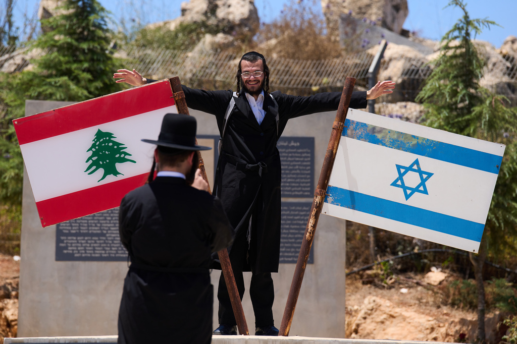 An Ultra-Orthodox Jewish man poses for a photo beside Israeli and Lebanese flags at a memorial site on the border with Lebanon in northern Israel, Wednesday, July 1, 2026. (AP Photo/Ariel Schalit)