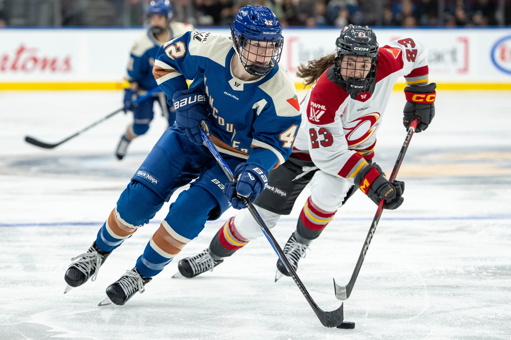 Vancouver Goldeneyes' Claire Thompson (42) and Ottawa Charge's Sarah Wozniewicz (23) vie for the puck during the third period of a PWHL hockey game in Vancouver, British Columbia, Tuesday, Dec. 16, 2025. (Ethan Cairns/The Canadian Press via AP)